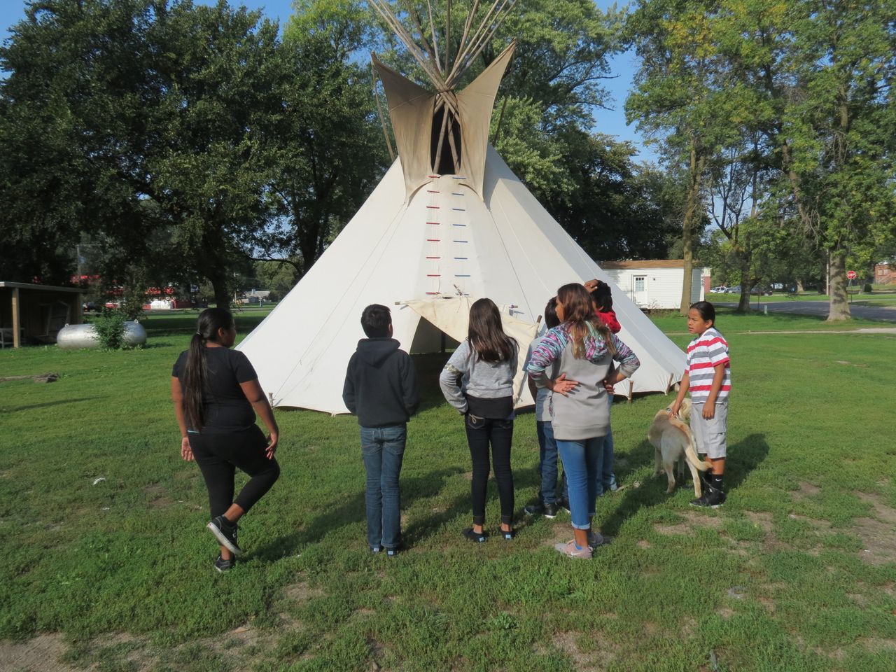 A middle school class from Umonhon Nation Public School, out on a cultural experience in the community, learning about the tipi. 