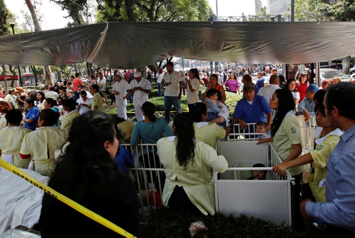 Nurses stand next to cribs with small children after they were evacuated