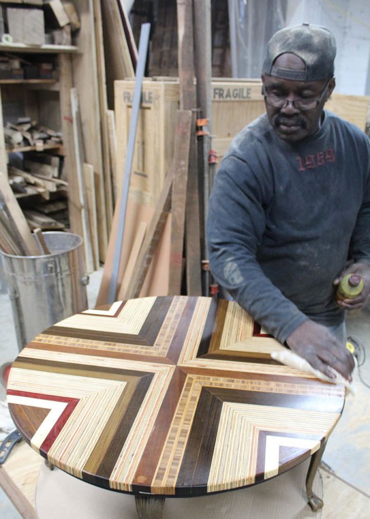 <p>Former inmate Gene Manigo puts the finishing touches on a table he created as part of the Refoundry initiative.</p>