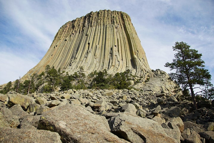 Devils Tower seen from the base. The many rocks and boulders, some house sized, form deep crevasses in which rattlesnakes and other animals seek refuge from the hot Sun. At least one rattler was seen this day near this spot. 