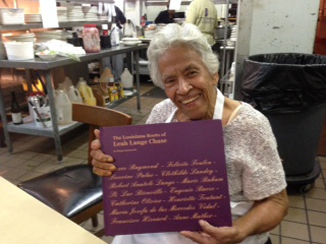 <em>Leah Chase holds book of her family history in her personal kitchen in Dooky Chase’s</em>