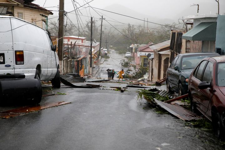 People walk on the street next to debris after the area was hit by Hurricane Maria in Guayama, Puerto Rico September 20, 2017.
