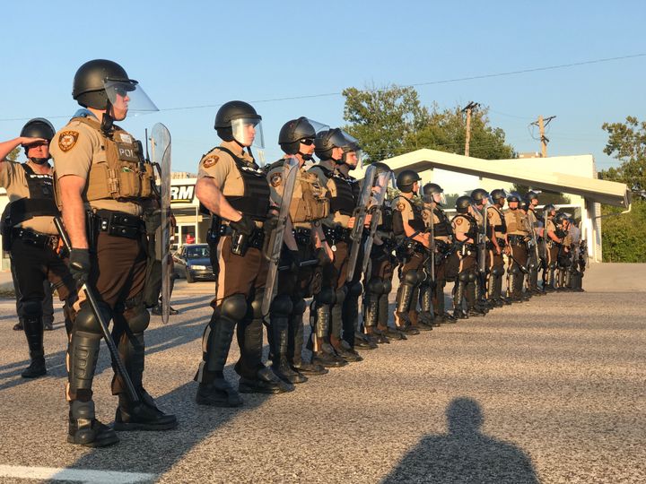 Riot police stand in a line near protesters in St. Louis County.