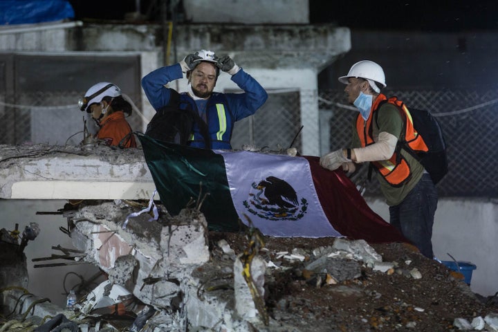 First responders place a Mexican flag over a collapsed building in Mexico City.