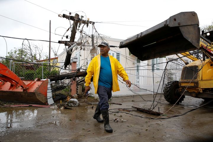 Workers use backhoe loaders to remove damaged electrical installations from a street in Salinas, Puerto Rico, Sept. 21, 2017.
