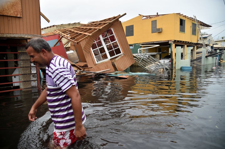 A man walks past a house lying in floodwater in Catano town in Juana Matos, Puerto Rico, on Sept. 21, 2017.