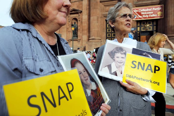 Becky Ianni (left) and Barbara Dorris, who were both abused by priests as children, hold photographs of themselves during Francis' 2015 visit to Philadelphia.