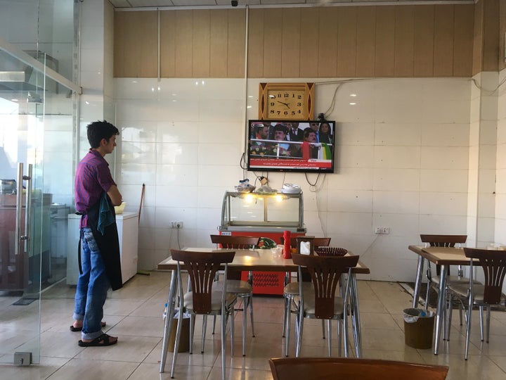 A restaurant worker watches Kurdish leader Masoud Barzani address a rally blocks away at football stadium, Erbil, Iraq, Sept. 22, 2017.