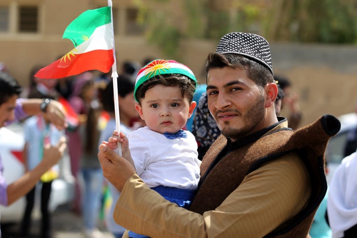 An Iraqi Kurdish man poses as he carries a child wearing the Kurdish flag on his head during a celebration in the northern ci