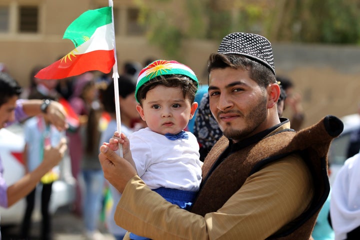 An Iraqi Kurdish man poses as he carries a child wearing the Kurdish flag on his head during a celebration in the northern city of Kirkuk on September 25, 2017.