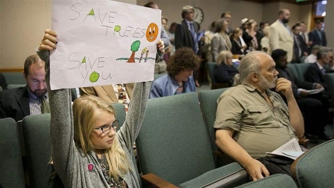 Jayden Malone holds up a sign during a hearing at the Texas Capitol in July on a bill that would have given private property owners complete control over the trees on their land. Texas lawmakers rejected the proposal, but it has spurred fears of a backlash against local tree ordinances.