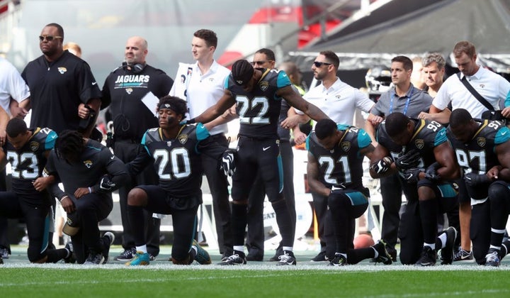 NFL players protest racial injustice by kneeling and locking arms during national anthem.