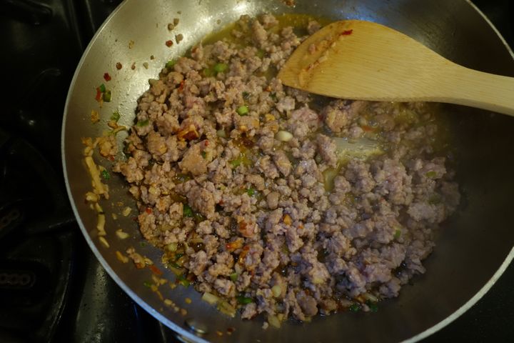 Once the peppers are done, use half the aromatics to flavor your ground pork