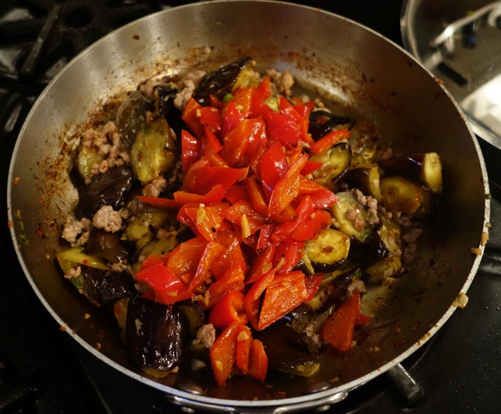 When the eggplant is tender, return the meat to the pan, then the peppers