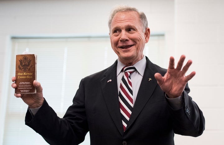 Moore holding a "One Nation Under God" pamphlet during a candidates' forum, Aug. 3. 2017.