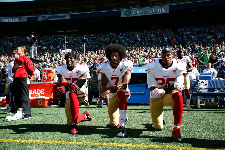 Colin Kaepernick #7 and Eric Reid #35 of the San Francisco 49ers kneel on the sideline during the anthem