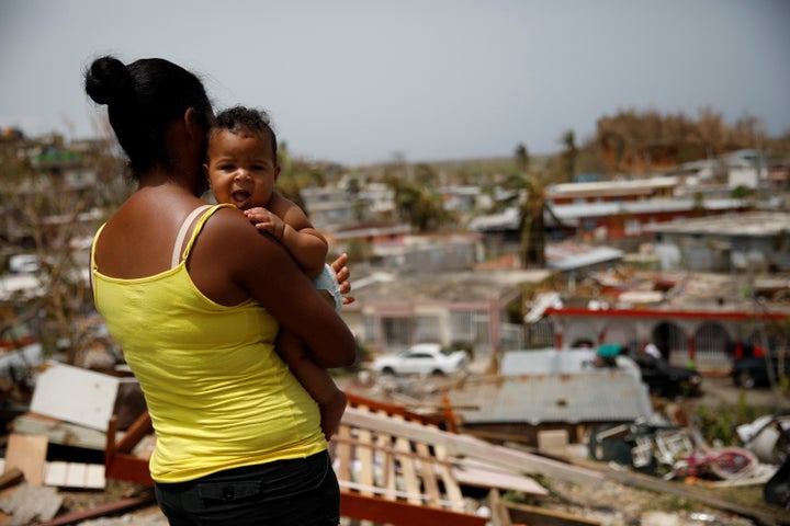 A woman carrying her baby looks at the damage in Canovanas on Sept. 26.