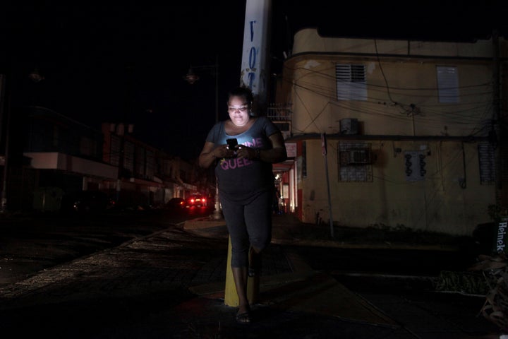 A woman uses her cell phone on a San Juan, Puerto Rico, street during a blackout on Sept. 25.