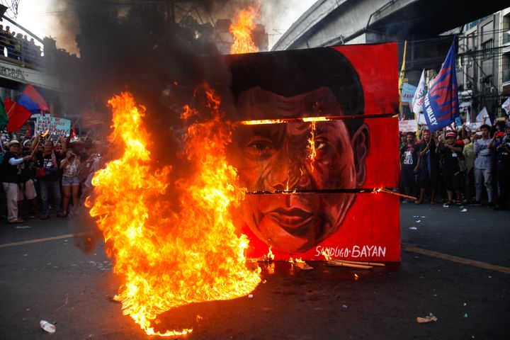 A cubic effigy painted with the face of President Rodrigo Duterte is set on fire by activists during a rally.