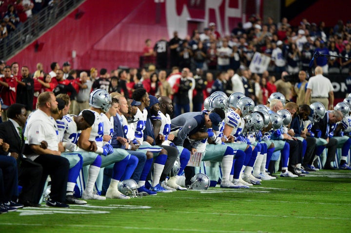 The Dallas Cowboys players, coaches and staff take a knee prior to standing for the National Anthem during a game against the