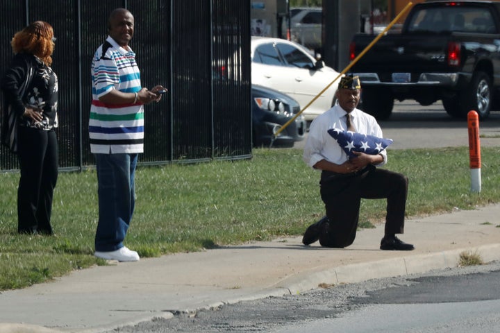 Marvin L. Boatright, as seen from President Donald Trump's motorcade, takes a knee while holding a folded American flag in Indianapolis, Indiana, on September 27, 2017.