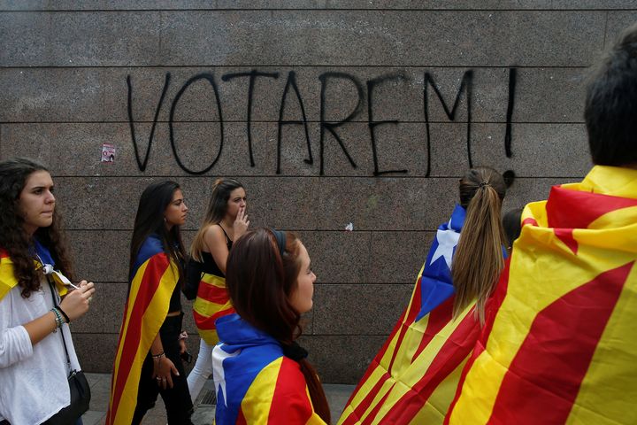 Students in Barcelona wear the Catalan separatist flag during a demonstration in favor of the independence referendum. The graffiti on the wall reads, "We will vote!"