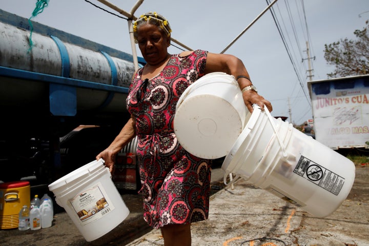 Post-Hurricane Maria, a woman carries buckets to be filled with water from a tank truck in Canovanas, Puerto Rico, on Sept. 2