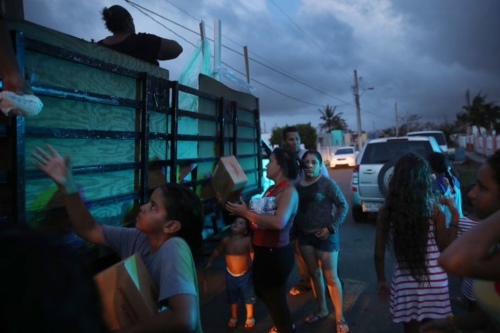 Hurricane survivors receive food and water being distributed by volunteers and municipal police as they deal with the aftermath of Hurricane Maria on Thursday in Toa Baja, Puerto Rico.