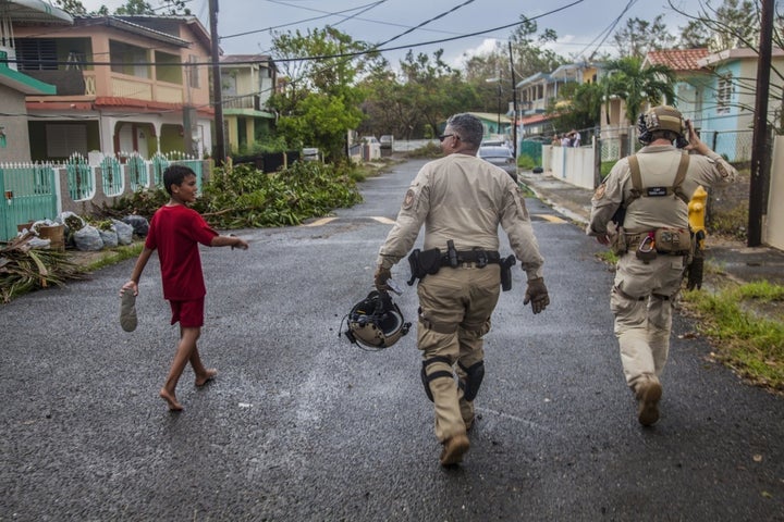 <p>A young boy walks with Air and Marine Operations agents as they walk through a neighborhood checking on residents outside of Ponce, Puerto Rico on Sunday, September 24.</p>