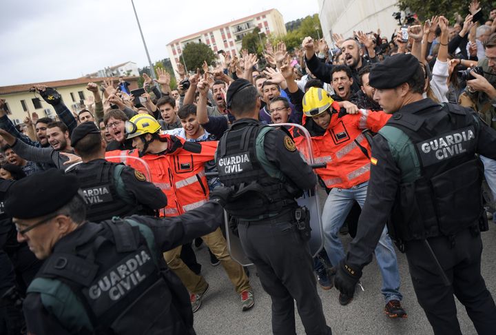 Firemen hold the people in front of Spanish Guardia Civil officers outside a polling station in San Julia de Ramis