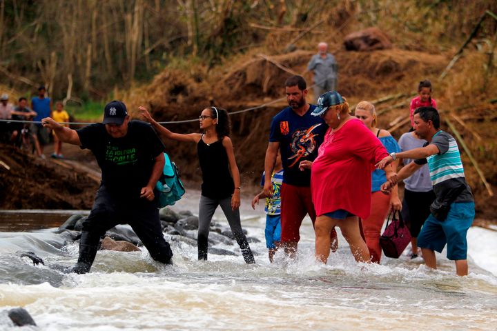 People wade into the San Lorenzo River after a bridge was swept away by Hurricane Maria in Morovis, Puerto Rico.