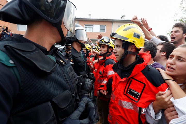 Firemen and people face off Spanish Civil Guard officers outside a polling station for the banned independence referendum in Sant Julia de Ramis, Spain Oct. 1, 2017.