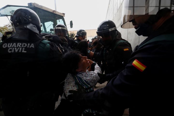 Spanish Civil Guard officers scuffle with a woman outside a polling station for the banned independence referendum.