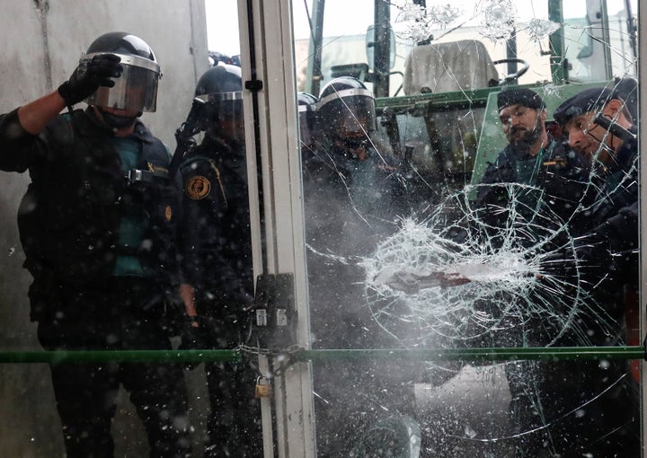 Spanish Civil Guard officers break through a door at a polling station for the banned independence referendum on Oct. 1,