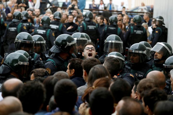 Scuffles break out as Spanish Civil Guard officers force their way through a crowd and into a polling station.