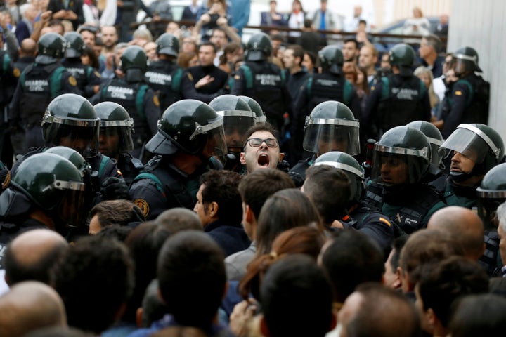 Scuffles break out as Spanish Civil Guard officers force their way through a crowd and into a polling station.