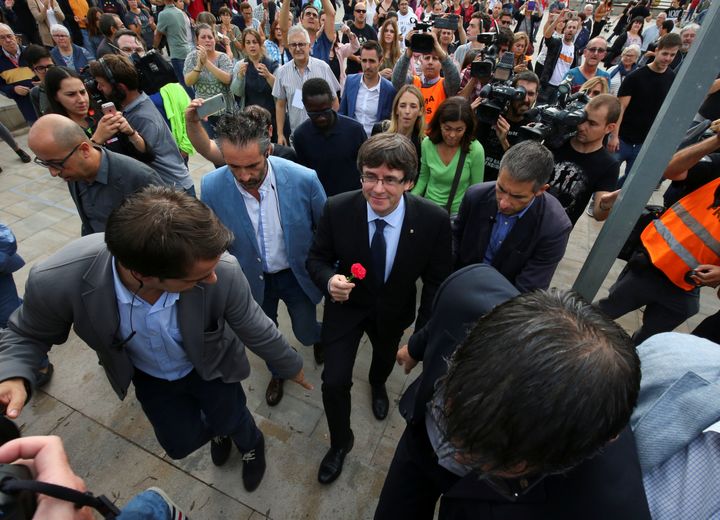 Catalan president Carles Puigdemont holds a carnation while visiting the polling station where he was expected to vote.