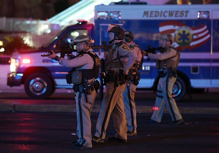 Police officers point their weapons at a car driving down closed Tropicana Ave near Las Vegas Boulevard after the shooting where 406 people were injured