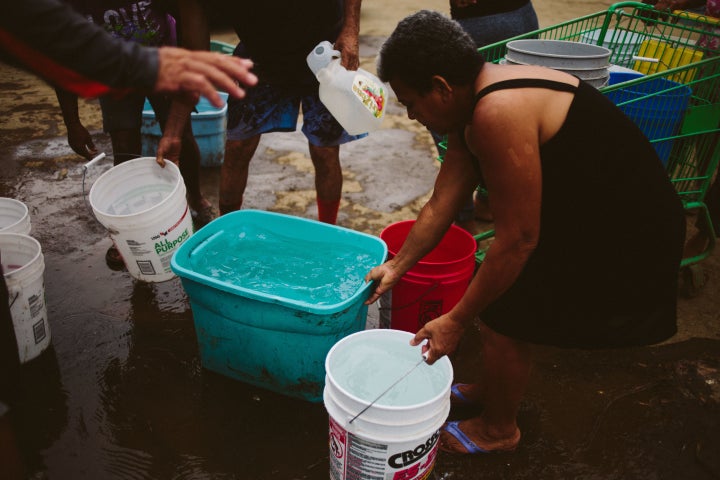 People fill buckets of water in Corozal, Puerto Rico, on Sept. 30. More than half of the island is currently without dri