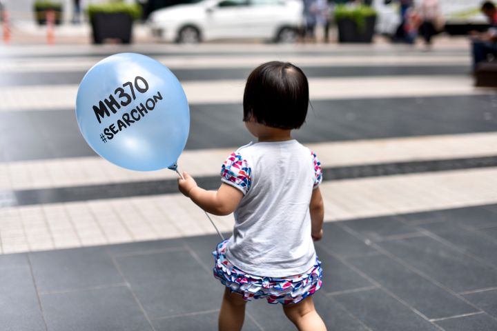 A little girl holds a balloon featuring the name of the missing flight at a memorial event in Kuala Lumpur in March 2017 