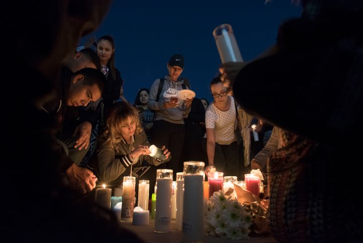 Mourners place candles and flowers on the ground during a candlelight vigil.