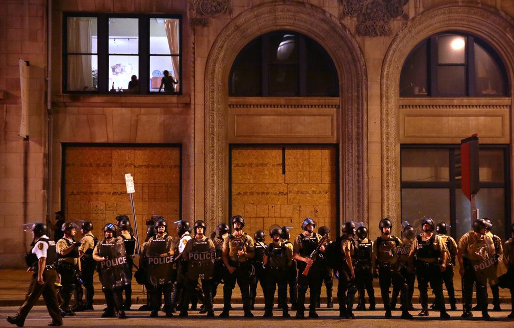 Residents watch as St. Louis County Police officers stand along Tucker Boulevard in downtown St. Louis as police order protesters to clear the area on Sunday, Sept. 17.