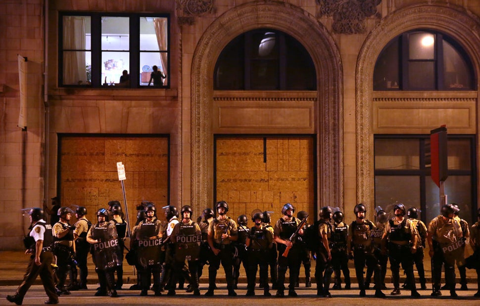 Residents watch as St. Louis County Police officers stand along Tucker Boulevard in downtown St. Louis as police order protes