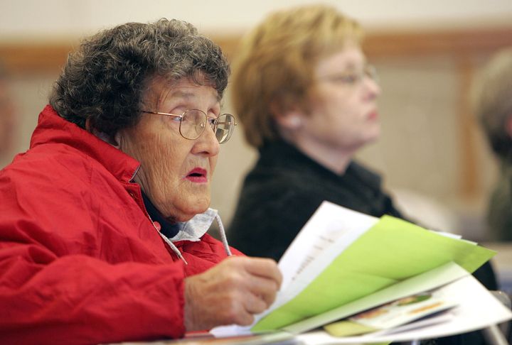 An elderly woman listens to a seminar on how to sign up during a Medicare enrollment event.