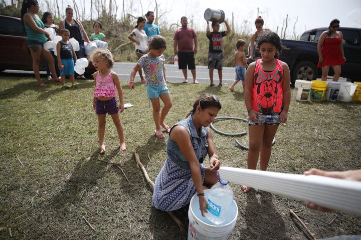 People in Corazal, Puerto Rico, fill containers with water from a natural spring on the side of the road as people deal with the aftermath of Hurricane Maria.