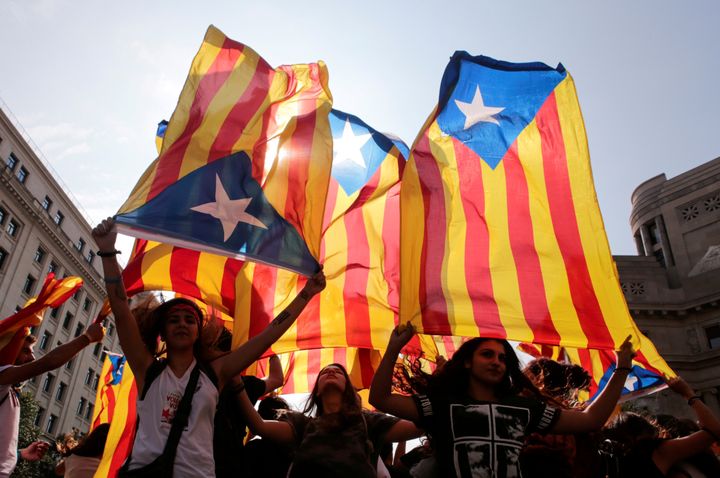 People hold on to Catalan separatist flags on top of an air vent during a demonstration two days after the banned independence referendum in Barcelona, Spain, October 3.