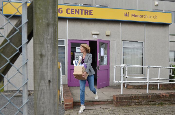 Unite is launching legal action on behalf of staff; a woman is pictured above carrying a cardboard box out of a Monarch office at Luton airport