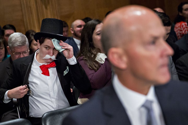 A demonstrator sits in costume behind Richard Smith, former chairman and chief executive officer of Equifax Inc., right, before a Senate Banking Committee hearing in Washington, D.C., on Wednesday, Oct. 4, 2017.