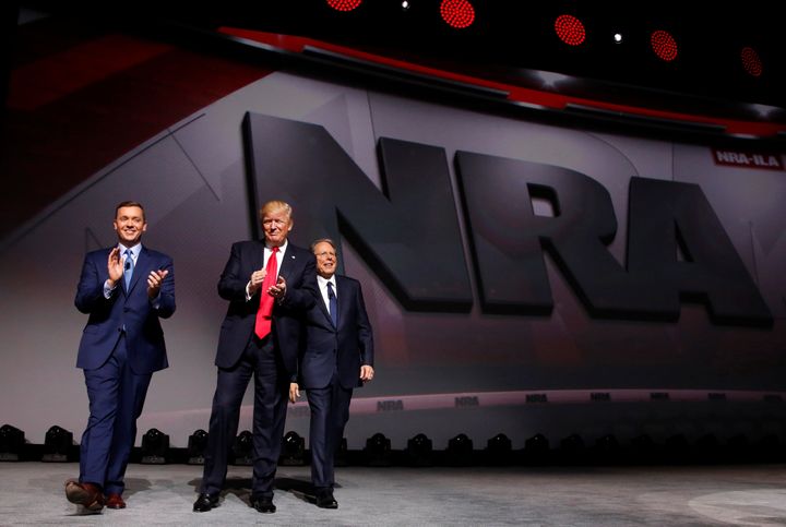 NRA Executive Director Chris Cox, left, and Executive Vice President and CEO Wayne LaPierre, right, welcome President Donald Trump onstage to deliver remarks at the National Rifle Association Leadership Forum in Atlanta on April 28, 2017.