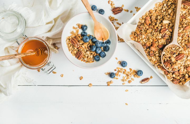 Healthy breakfast set. Oat granola with nuts, yogurt, honey and blueberries in bowl on white wooden background, top view, copy space, horizontal composition Foxys_forest_manufacture via Getty Images